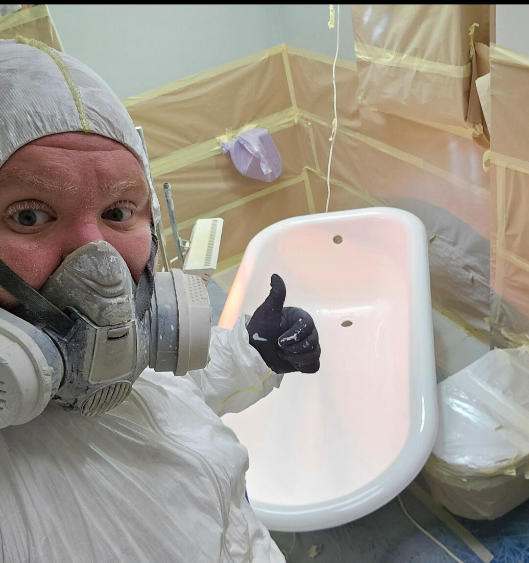 photo of glossy baths owner photo of glossy baths re-enamelling owner Seamus with a thumbs up, in ppe, in a room full of masking up and a completed bath in Oxford